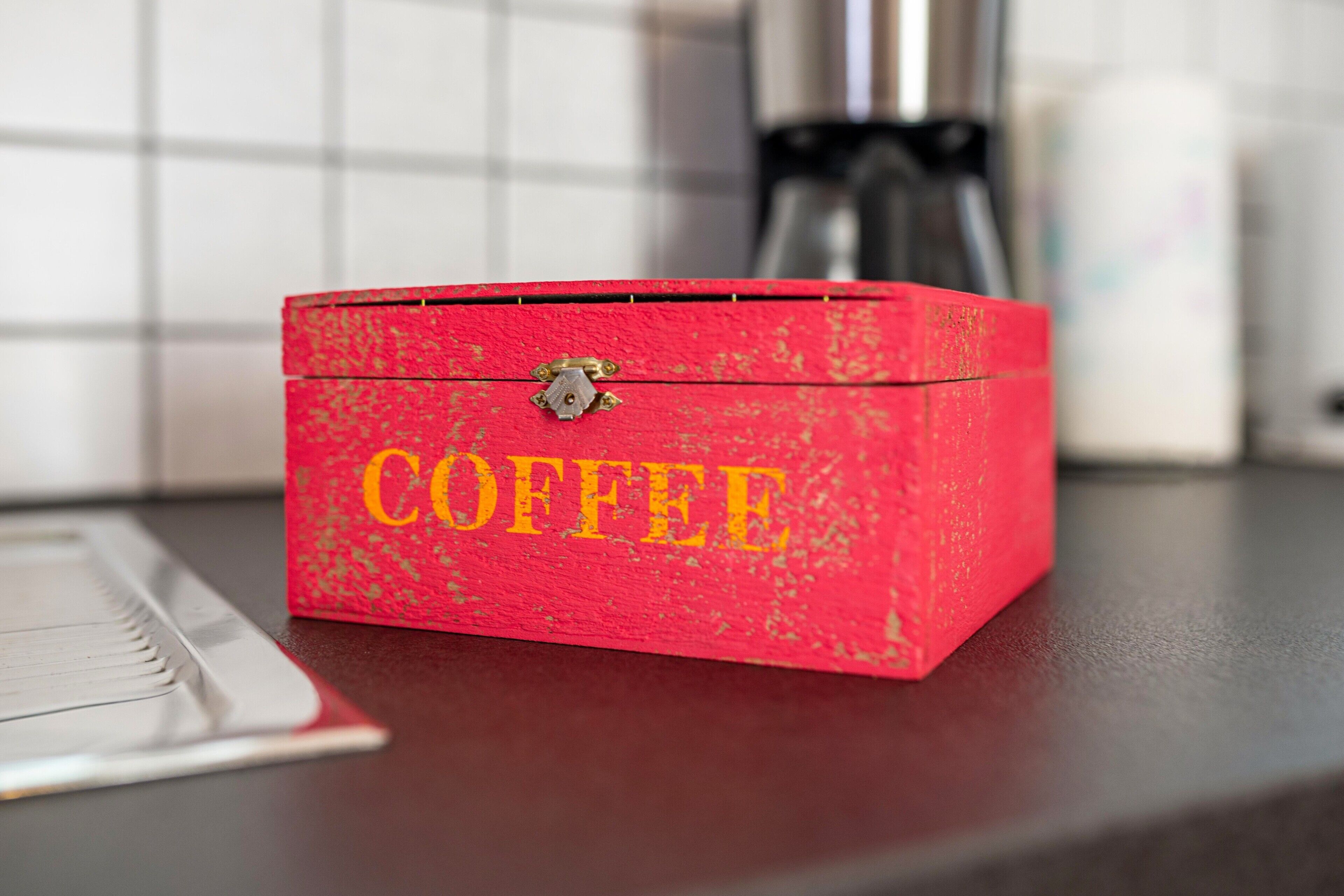 Une boîte rouge sur laquelle est inscrit le mot « CAFÉ », posée sur un comptoir.