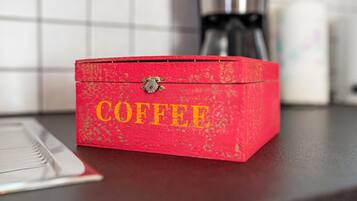 Une boîte rouge sur laquelle est inscrit le mot « CAFÉ », posée sur un comptoir.