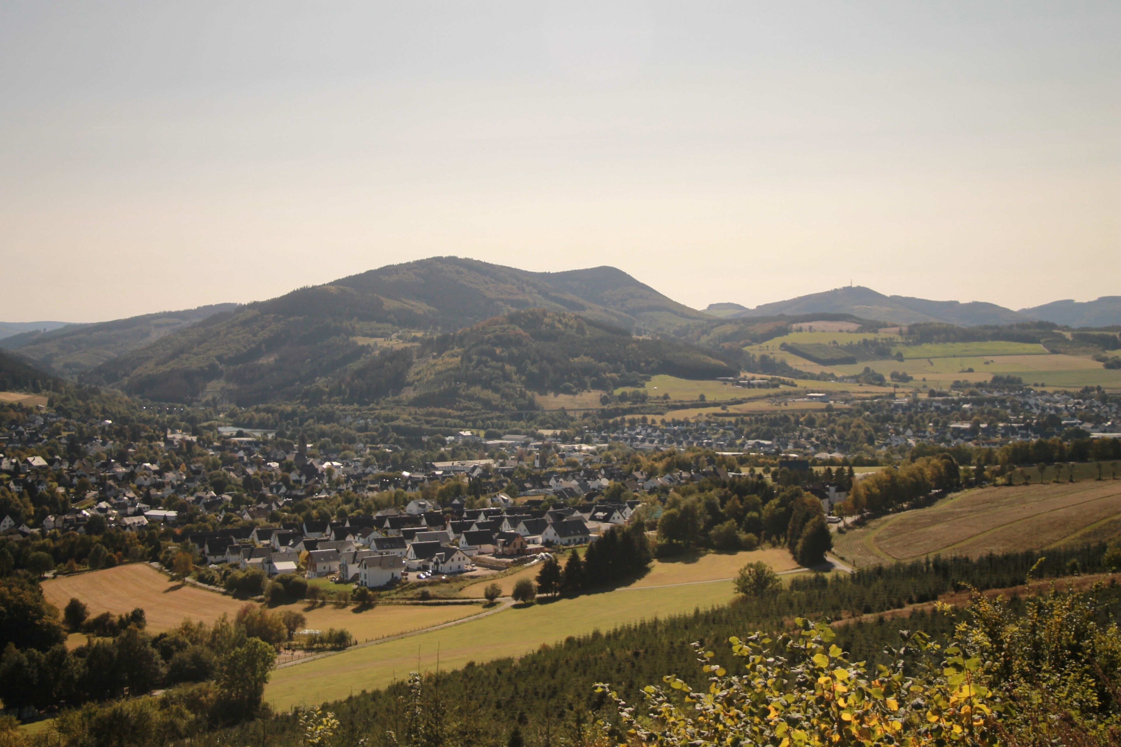 A town nestled in a valley with rolling hills in the background.