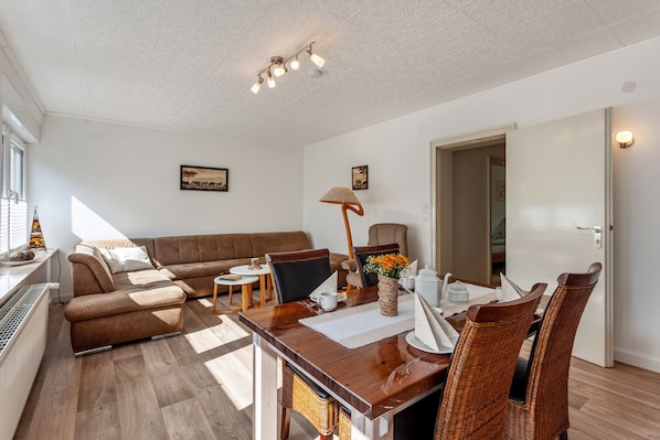 A modern living room with a sofa, dining table, chairs, and a lamp.