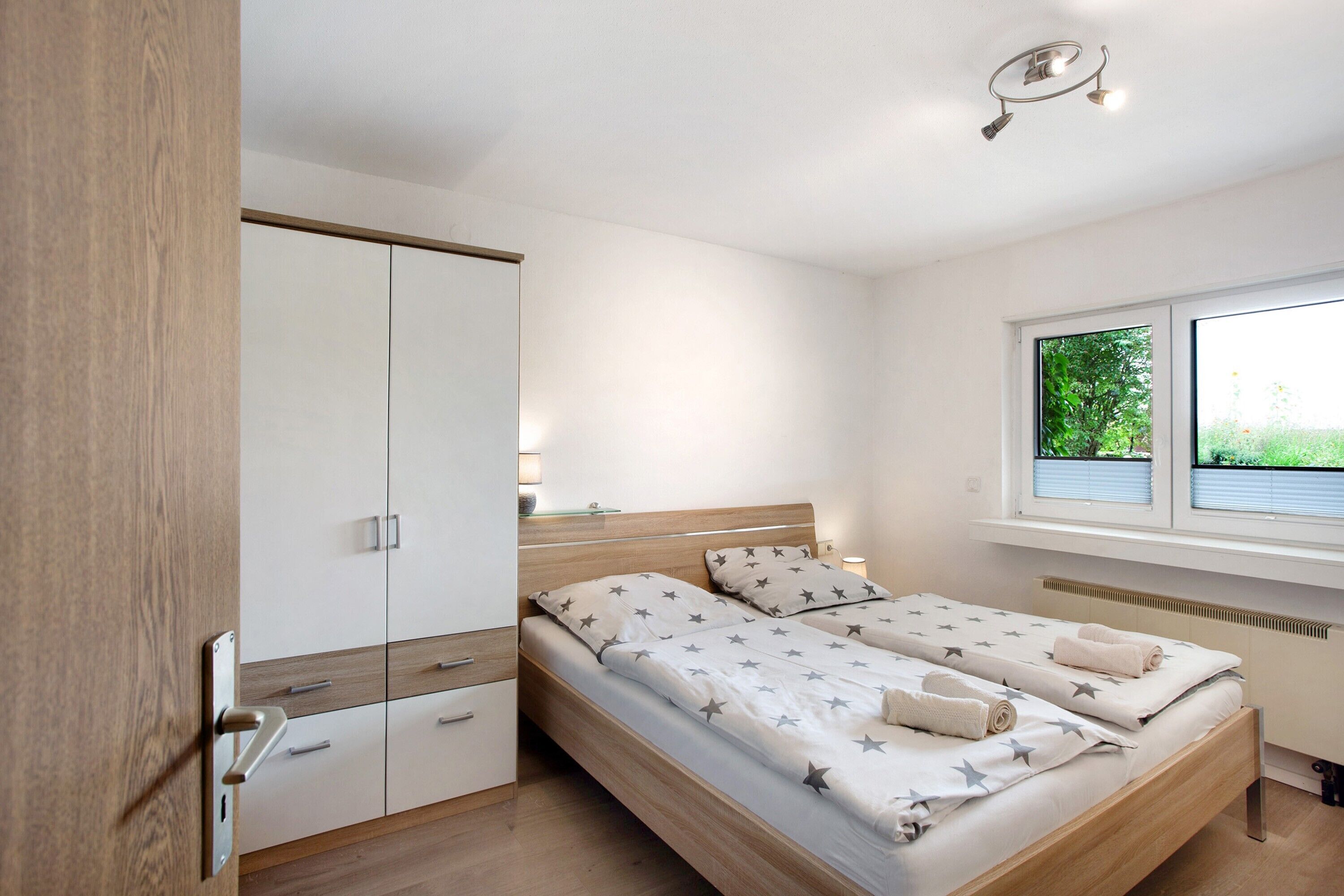 Un dormitorio con cama, armario, ventana con vistas y lámpara de techo.