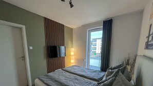 Une chambre d’hôtel avec deux lits, un téléviseur fixé au mur, une fenêtre avec des rideaux et un radiateur.
