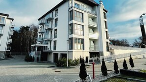 Un immeuble à plusieurs étages doté de balcons, d’une cour pavée et d’un petit élément décoratif aquatique.
