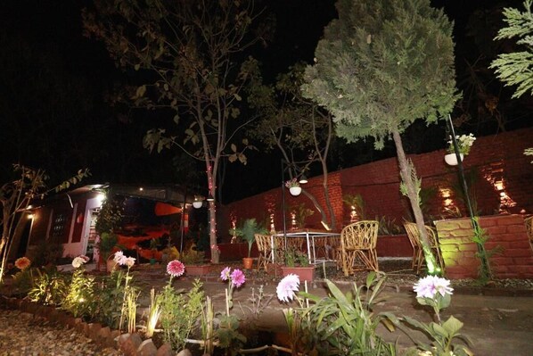 An outdoor seating area with tables and chairs, surrounded by potted plants and flowers.