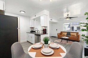Cozy living space with a dining area for four, kitchen, sofa, and coffee table.