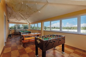 A room with a foosball table, pool table, and windows with a view of greenery. - Pool Villa Divina (Liznjan)
