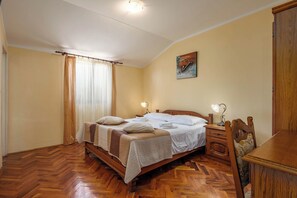 Ein Schlafzimmer mit einem hölzernen Bett, einem Nachttisch mit Lampe, einem Holzstuhl und einem Holzschrank.