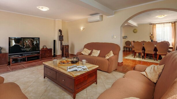 A living room with a TV, sofa, coffee table, and dining area. - Pool Villa Divina (Liznjan)