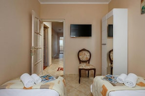 A hotel room with two beds, a television, a chair, and a wardrobe. - Pool Villa Divina (Liznjan)
