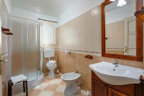 Un baño con ducha, inodoro, bidé, lavabo y espejo.
