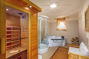 Un baño moderno con sauna de madera, ducha con mampara de vidrio, bañera grande y banco de madera.