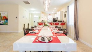 A dining area with a long table set for a meal, chairs, a chandelier, and a painting on the wall. - Spacious 5BR, Private Pool, Beautiful Decor (Davenport)