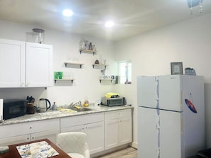 Compact kitchen area with a dining table and chairs, featuring a microwave, toaster, and refrigerator.