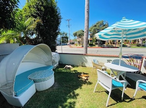 Relax on the patio with a clear view of the surrounding neighborhood, featuring a comfortable bench, small table, and umbrella for shade.