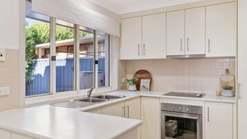 A modern kitchen with a large window, stainless steel appliances, and light-colored cabinetry.