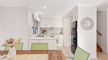 A modern kitchen with white cabinets, a central island, and a stainless steel refrigerator.