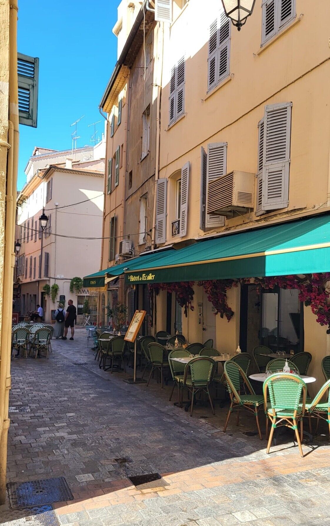 A narrow street with outdoor seating at a restaurant.