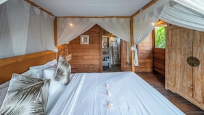Un dormitorio acogedor de estilo cabaña de madera con cama con dosel, un armario de madera y vistas a un jardín exuberante.