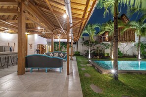 A covered outdoor area with a pool, lounge chairs, and a bar. - Villa Palm Tree (Seminyak)