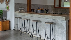 Una cocina con barra, taburetes, ventilador de techo y un espejo grande.