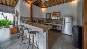 Una cocina moderna con una isla central, taburetes de bar, un refrigerador y un ventilador de techo.