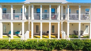 A two-story building with balconies, a covered porch, and outdoor seating. - Sandy Feet Retreat|Heart of Destin|Community Pool (Destin)