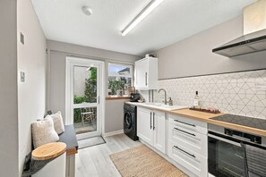 A compact kitchen with a washing machine, a sink, and a stove.