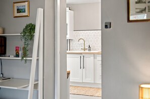 Une cuisine moderne avec des meubles blancs, un pare-feu géométrique et un robinet doré.