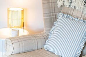 A cozy corner with a plaid sofa, striped pillows, and a lamp. - Heatherwood Cottage - Central Scone (Scone)