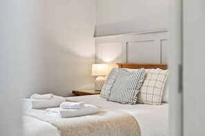 Une chambre d’hôtel avec un lit bien fait, une lampe de chevet et une table de chevet avec une lampe.