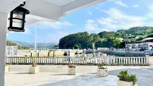 A waterfront view with a marina, a white building with a balcony, and a stone wall.