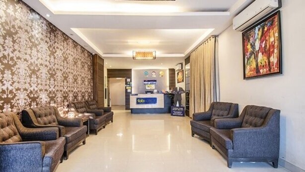 A hotel lobby with a reception desk, plush seating, and a large painting on the wall. - Fabhotel Celebrity Layout (Bengaluru)