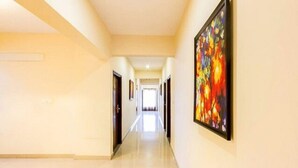 A hotel hallway with a modern design, featuring a long corridor with doors on both sides and a large abstract painting on the right wall. - Fabhotel Celebrity Layout (Bengaluru)