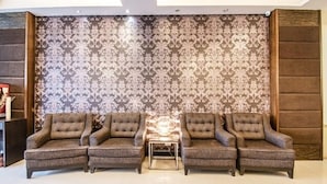 A living room with a patterned wallpaper, two sofas, and a small coffee table. - Fabhotel Celebrity Layout (Bengaluru)