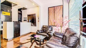 Una sala de estar moderna con un sofá de cuero, una mesa de centro de vidrio y piso de madera.