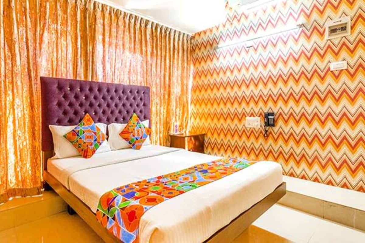 Una habitación de hotel con cama, cortinas y una pared con diseño.