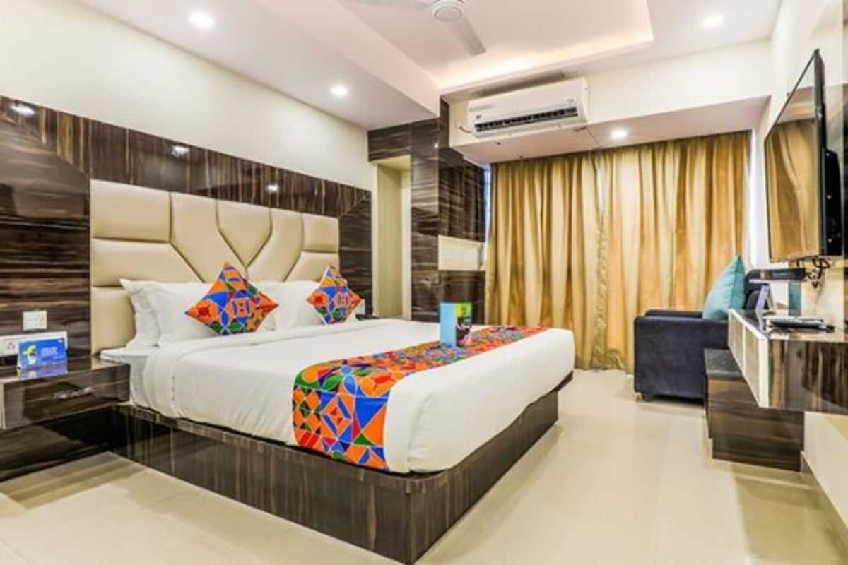 Una habitación de hotel moderna con una cama grande, un escritorio y un televisor.