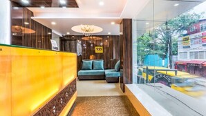 A reception area with a sofa, a chandelier, and a glass wall with a view of the street. - Fabhotel Khb Tower (Bengaluru)