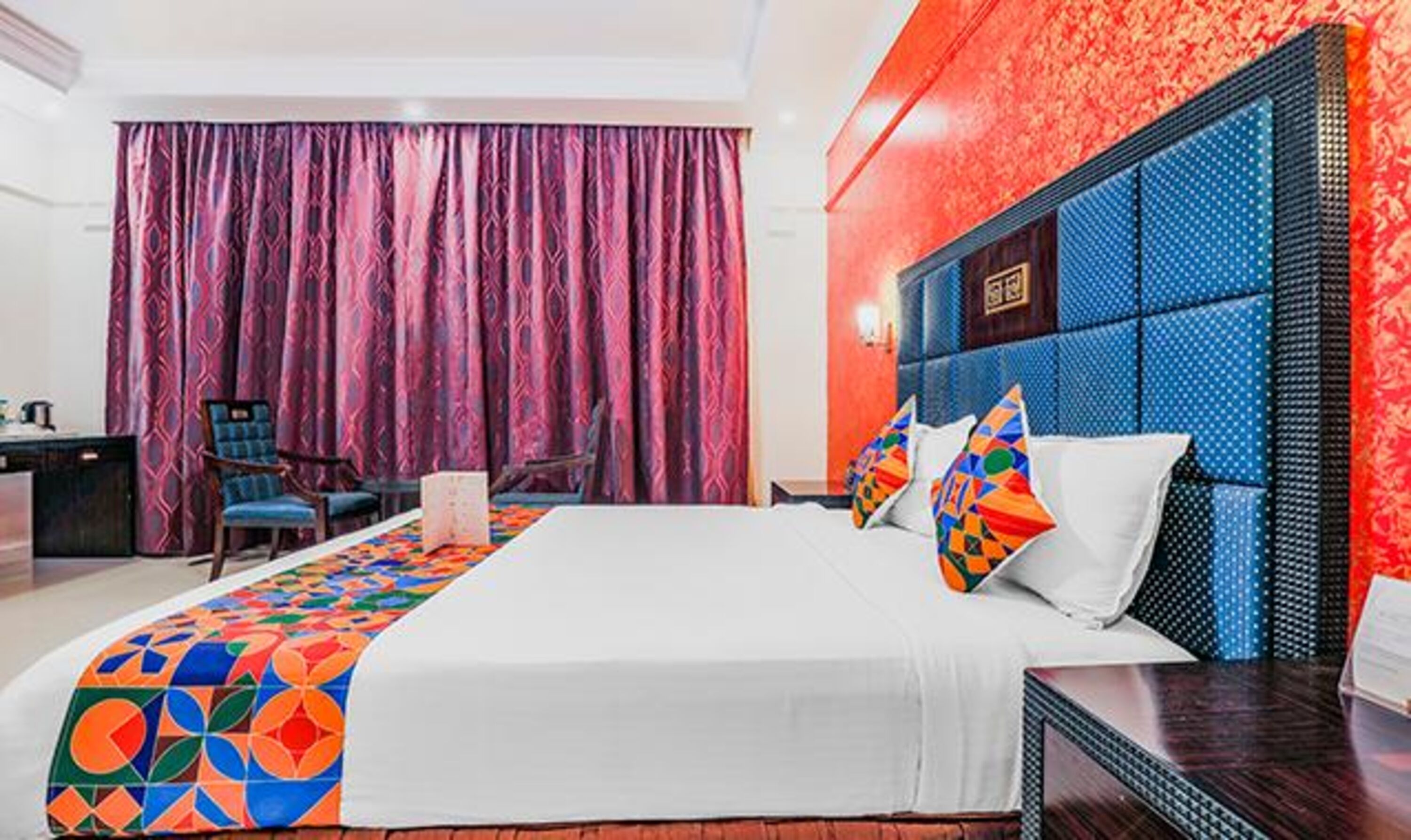 A hotel room with a large bed, a desk, and a chair.