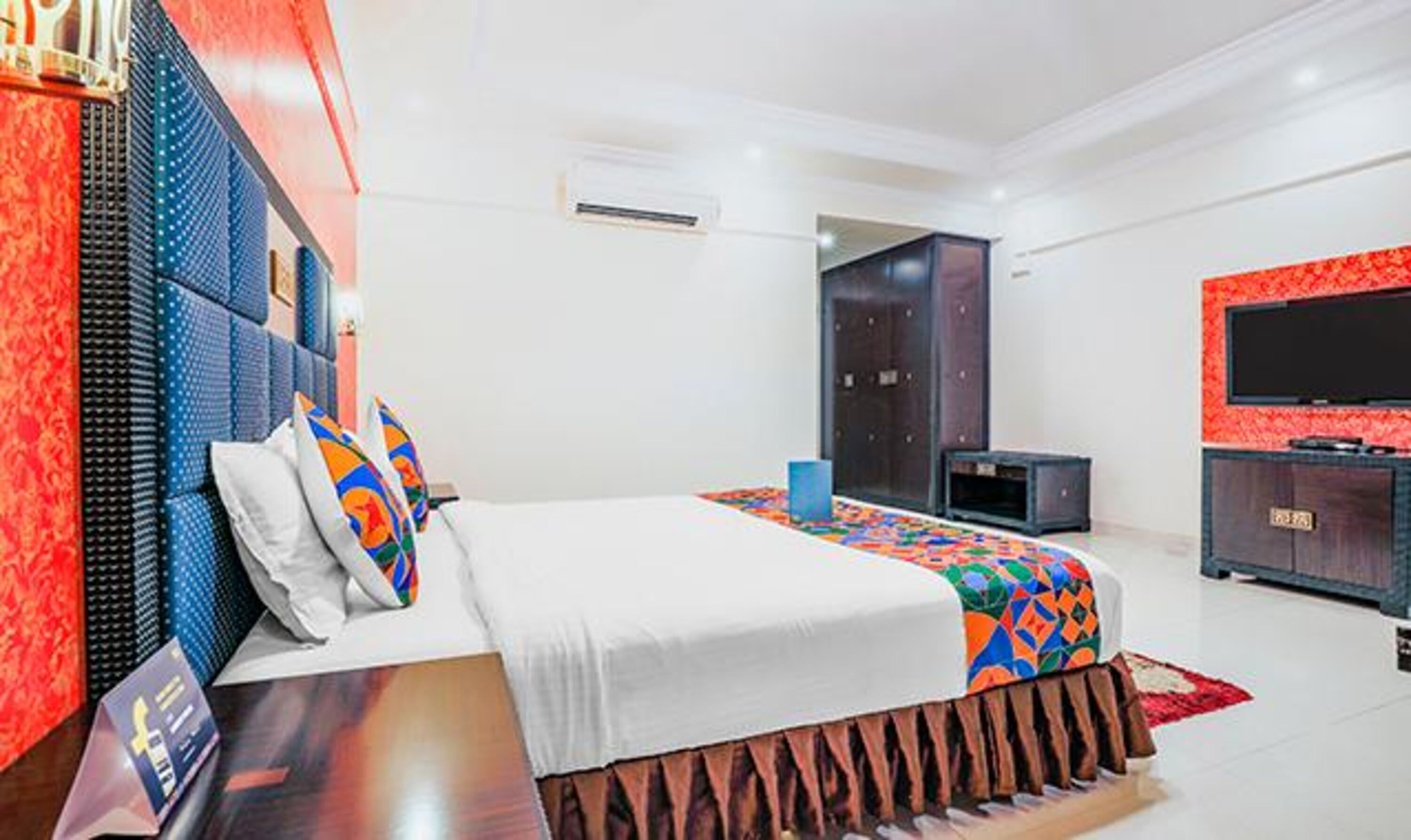 A modern hotel room with a large bed, a TV, and a wardrobe.