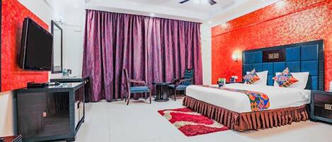 A hotel room with a bed, a desk, a chair, a television, and a ceiling fan.