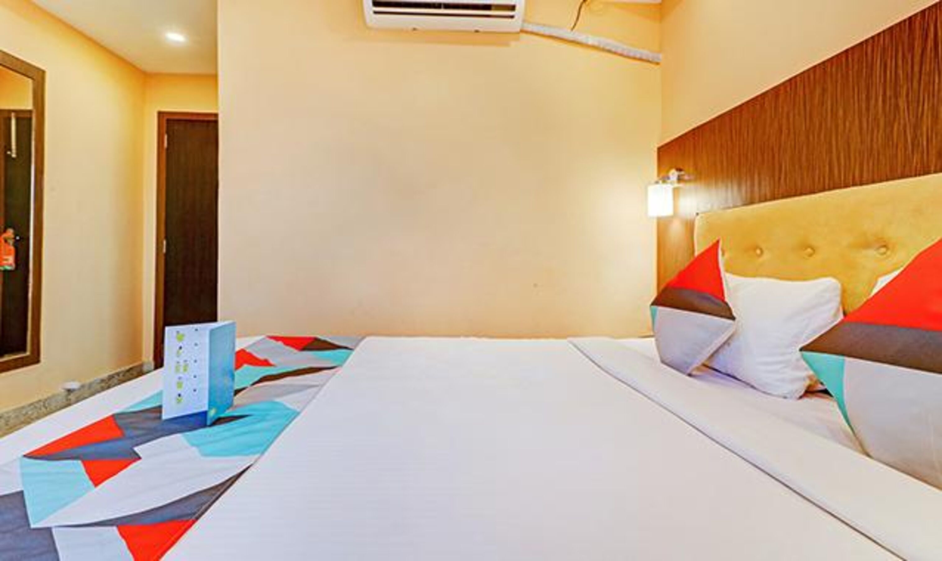 Hotelkamer met een bed, een houten hoofdbord, een wandairconditioner en een deur.