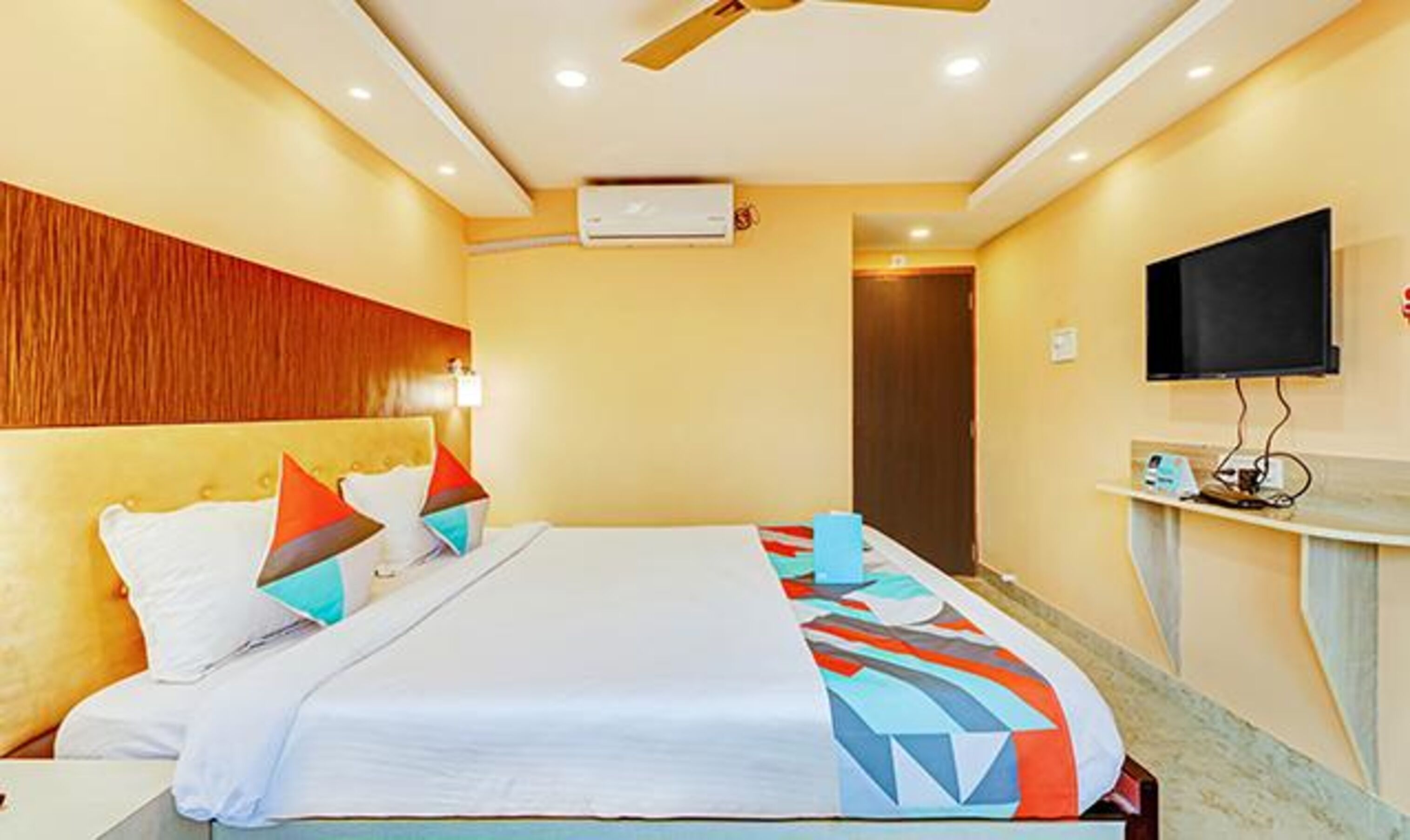 Ein Hotelzimmer mit Bett, Flachbildfernseher an der Wand und Deckenventilator.