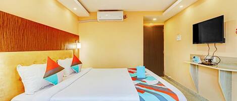 Ein Hotelzimmer mit Bett, Flachbildfernseher an der Wand und Deckenventilator.