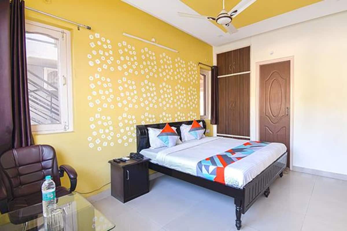 A bedroom with a bed, a desk, a chair, a wardrobe, and a ceiling fan.