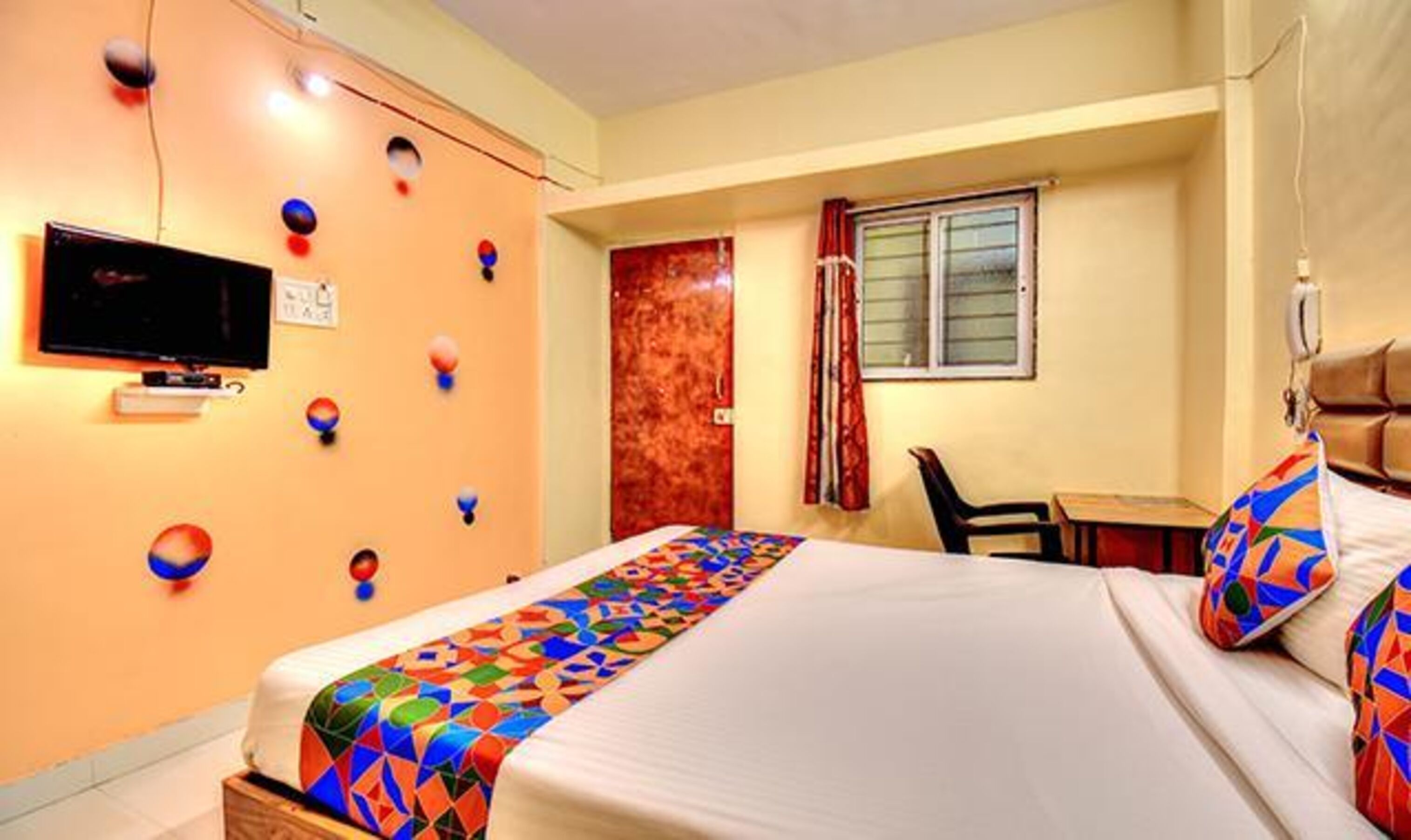 A hotel room with a bed, a television, a desk, and a chair.