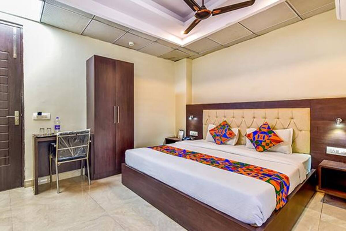 Una habitación de hotel con cama, escritorio, armario y ventilador de techo.