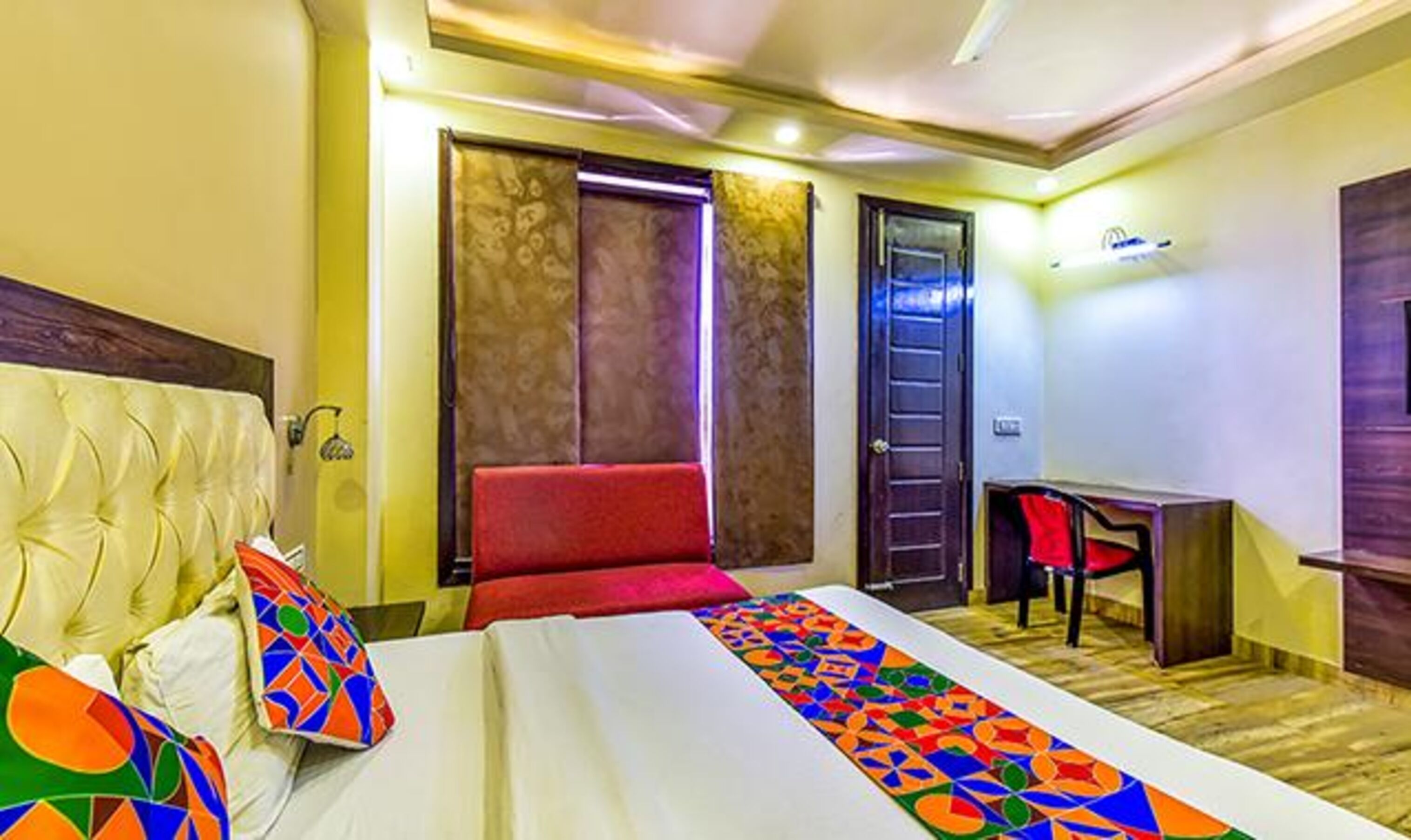 A hotel room with a bed, a desk, and a red chair.