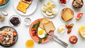 A breakfast spread with toast, eggs, strawberries, and various condiments.