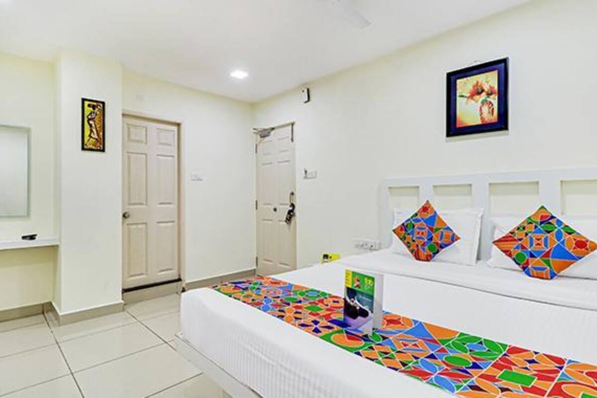 Une chambre d’hôtel avec un lit, une table de chevet, une télévision et une porte.